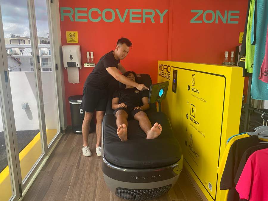 A staff member showing a member how to start a session on the HydroMassage lounger
