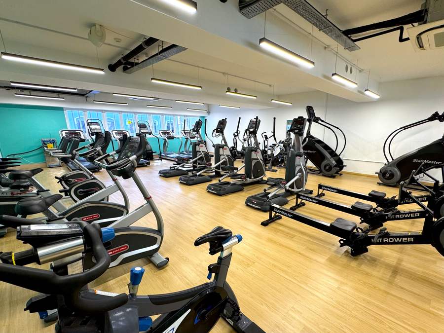 Wide view of the cardio floor with rows of Star Trac bikes and treadmills, ellipticals, StairMaster steppers and rowers on a wooden floor