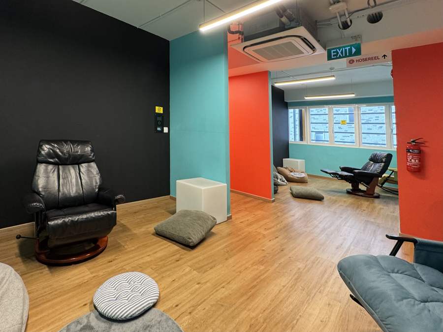 The wider chill zone with leather recliners, floor cushions and bean bags across colour-blocked black, teal and red walls